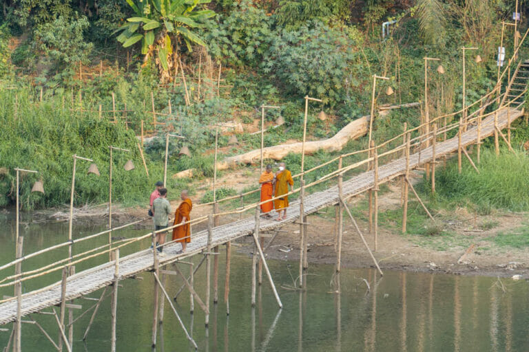 Mönche queren die Bambusbrücke